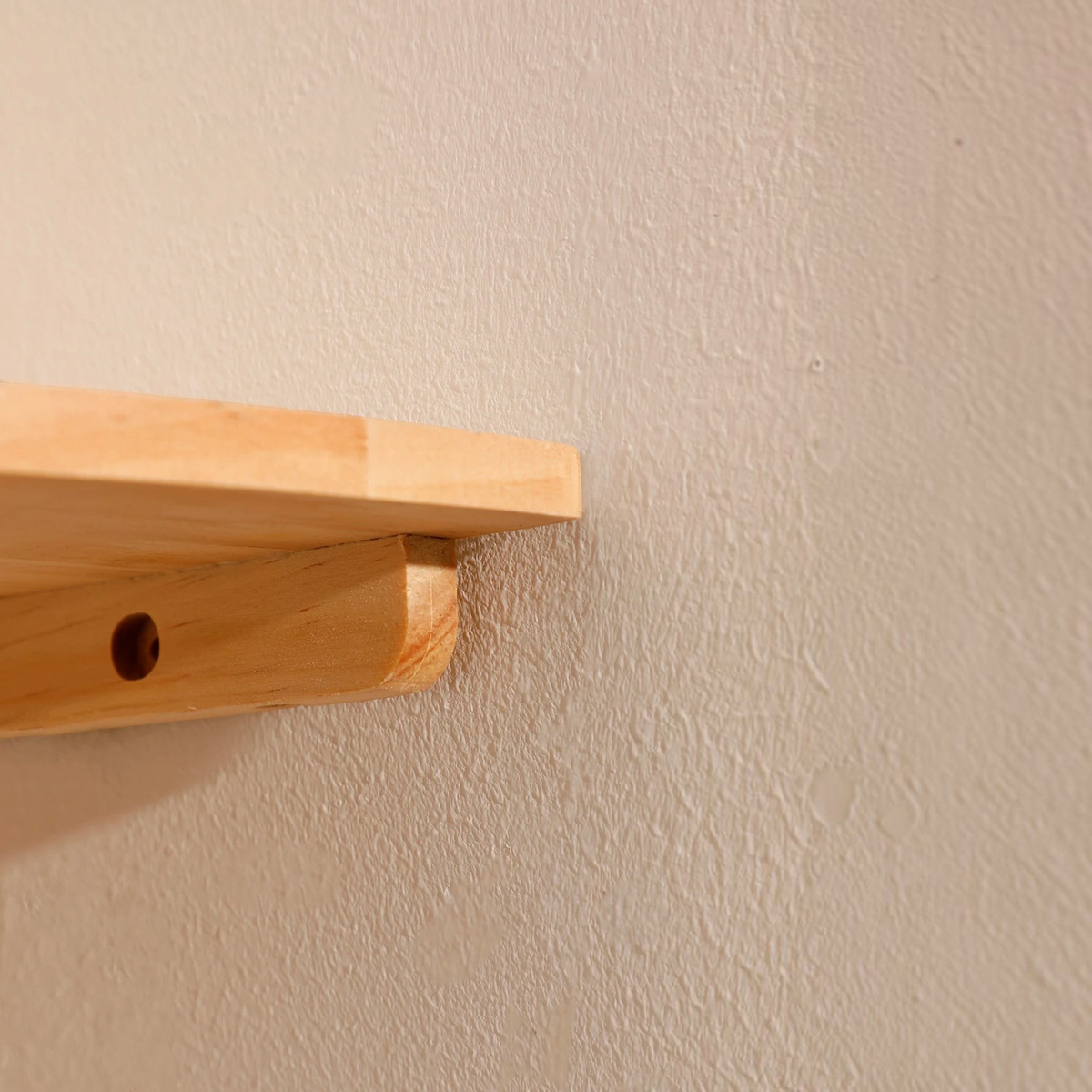 Étagère murale d'angle en bois clair Cornelia par Royaume de L'Étagère fixée sur un mur blanc