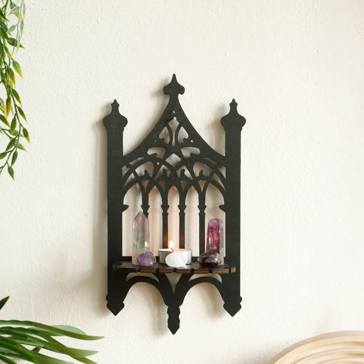 Étagère murale en bois noir Royaume de L'Étagère au design gothique avec bougie et cristaux sur un mur blanc