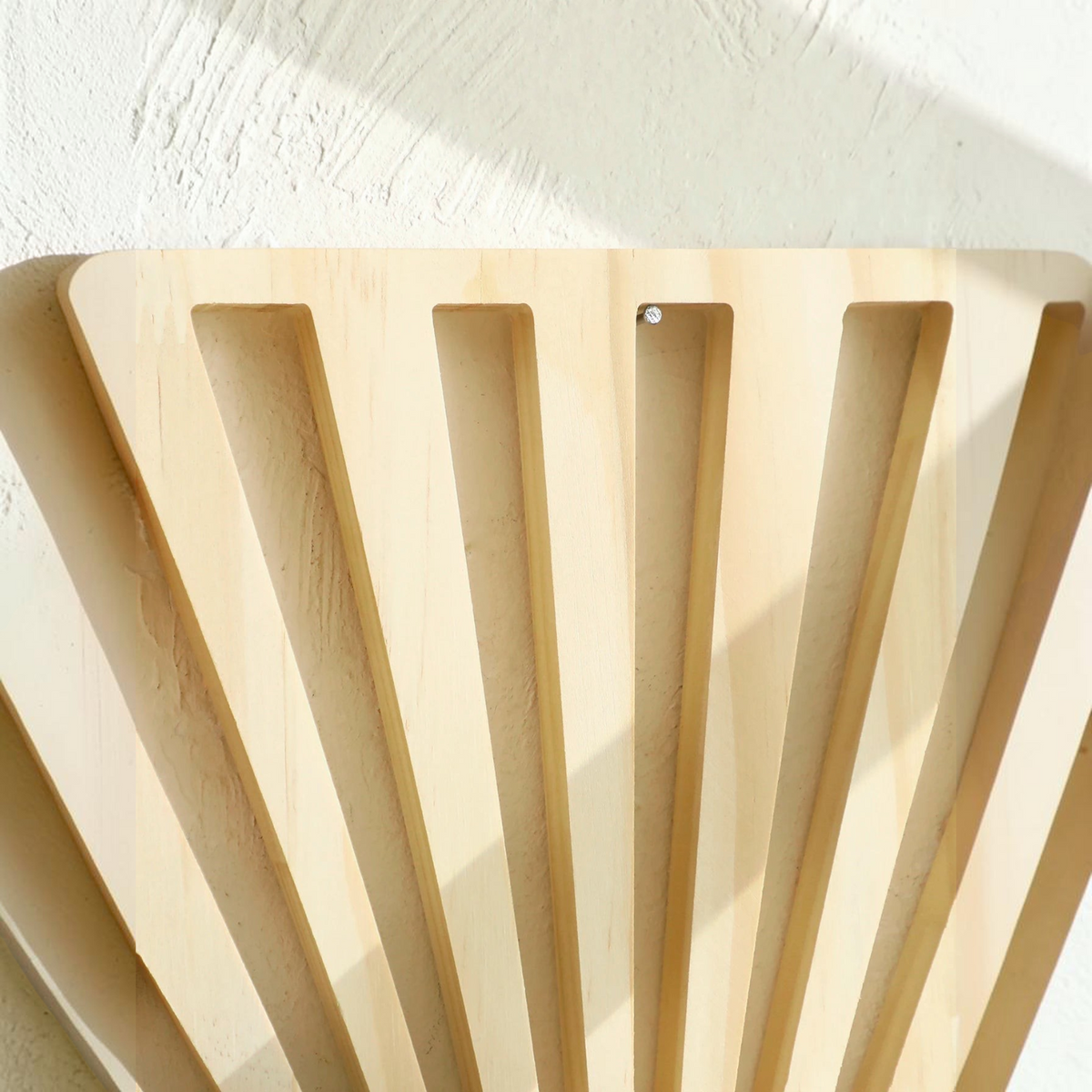 Gros plan sur le motif soleil ajouré en bois naturel de l'étagère murale Noela par Royaume de L'Étagère