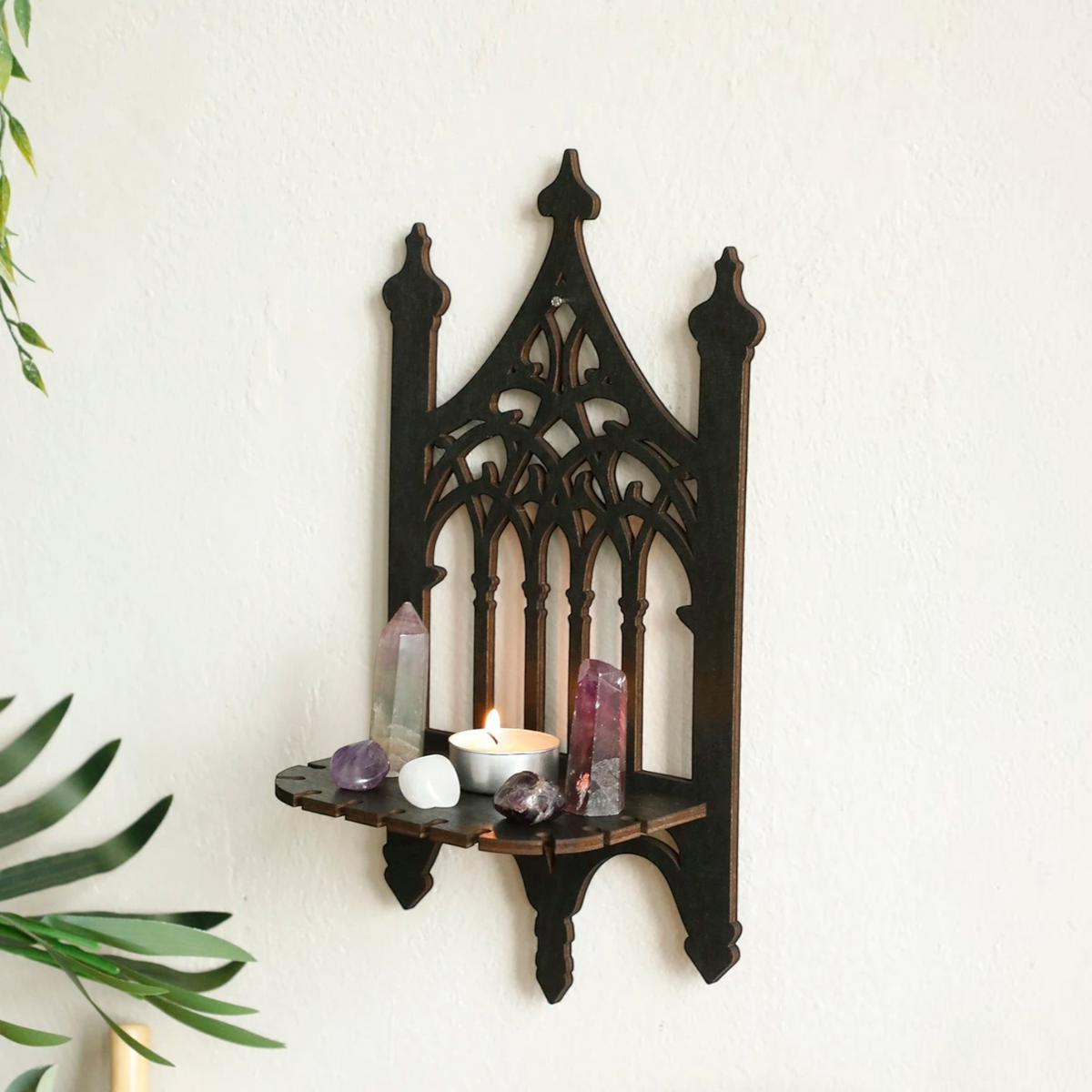 Étagère murale Royaume de L'Étagère en bois noir style gothique avec des cristaux et une bougie sur un mur blanc